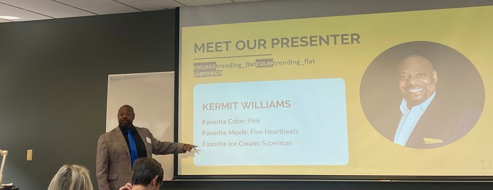 Kermit Williams presenting to an audience, standing beside a slide that reads Meet Our Presenter